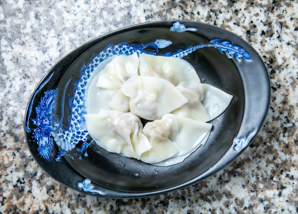 「京都点心福の海老水餃子、餃子の皮に海老と豚肉の餡をのせて包み始める様子。職人の仕込み工程・手作りの一手目」